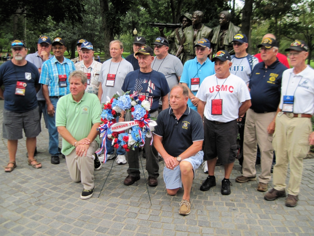 Assemblyman Steve Hawley [right of wreath] poses for a photo with Assemblyman Michael DenDekker [left of wreath] and veterans in front of the Vietnam War Memorial during 2018’s Patriot Trip to Washington D.C.